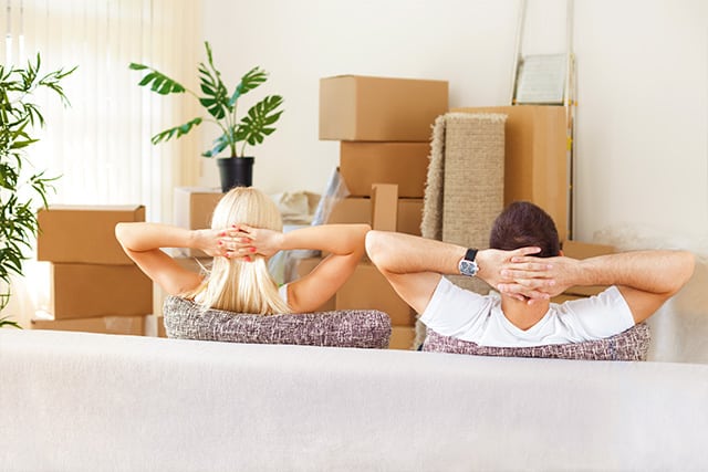 A couple relaxing wth their hands behind their head as professionals take care of a move with white glove service