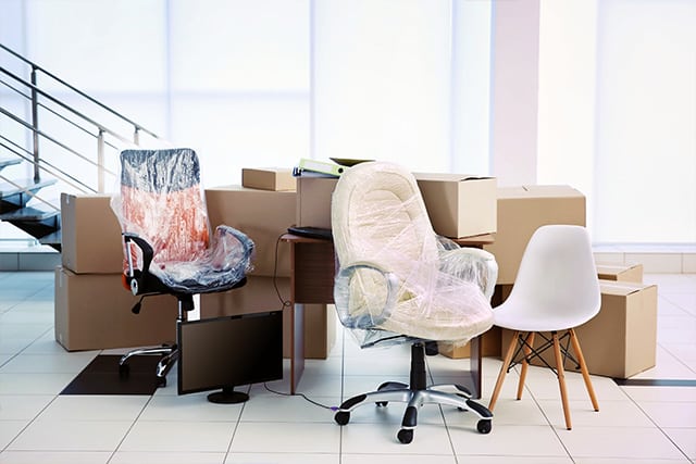 Cardboard boxes, monitors, desks and chairs wrapped in preparation for a business move